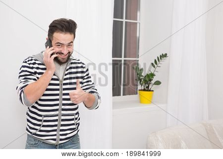 Smiling young man talking on the phone at home.