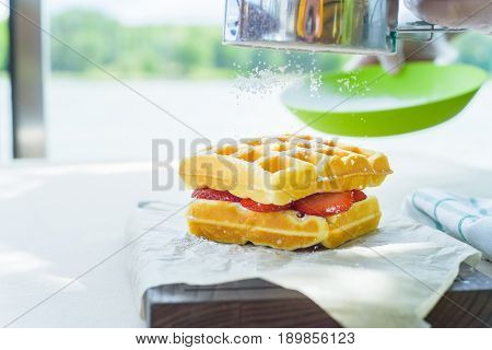 Close up sugar powder put on top of belgian waffles with strawberry