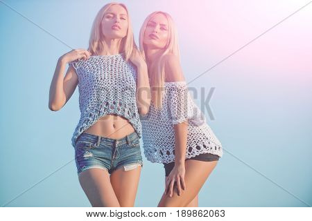 Twin Sisters With Long, Blond Hair Posing On Sunny Day