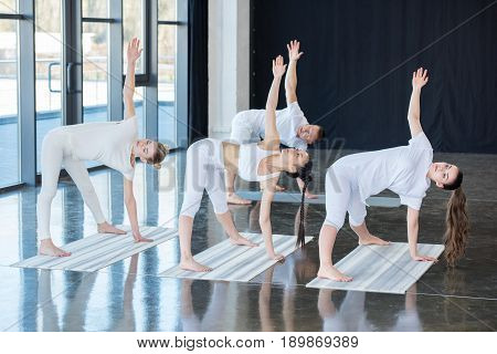 Girls Doing Half Moon Pose (ardha Chandrasana) With Instructor Indoors