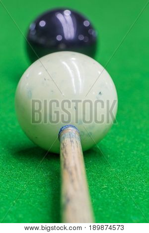 Selective focus on cue and white snooker ball dirty blue chalk powder with blurred black snooker ball billiard playing.