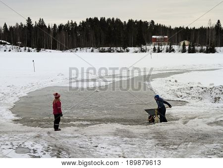Children Are Playing With Snow At Frozen River In Rovaniemi, Finland