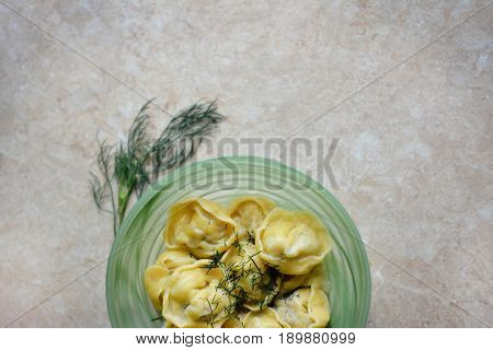 Dumplings in the green bowl on the stone table with greens in details