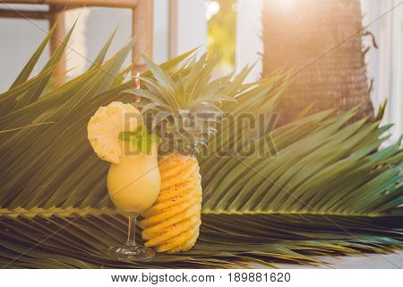 Pineapple And Pineapple Smoothies Against The Background Of A Branch Of A Palm Tree