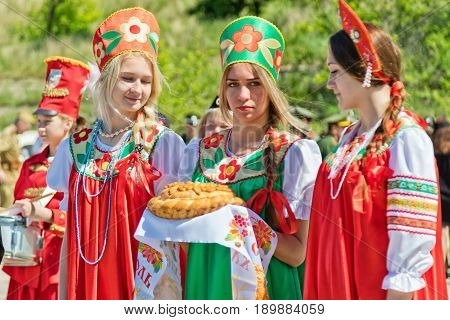 Three Girls In Russian Folk Costumes Is Waiting For Guests With Traditional Bread And Salt