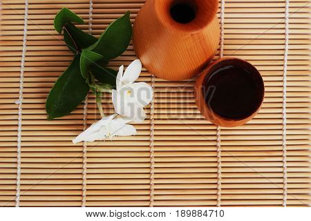 SAKE liqueur in a brown wooden bottle on a light brown background.