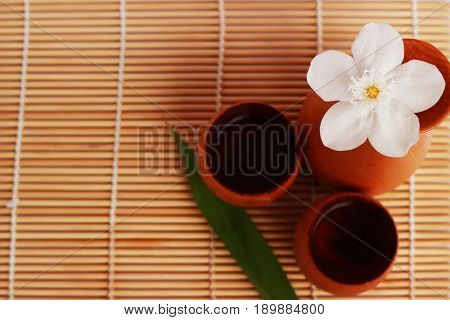 SAKE liqueur in a brown wooden bottle on a light brown background.