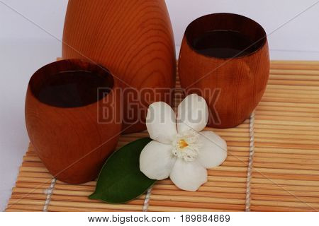 SAKE liqueur in a brown wooden bottle on a light brown background.