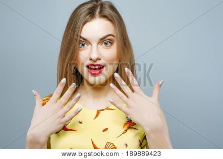 Temperamental Woman Wearing Yellow Bright Dress Is Looking At The Camera On Grey Background. Portrai