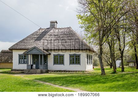 Ancient peasant Ukrainian house in the spring with a thatched roof in the old village of national architecture Ukraine. Ancient peasant Ukrainian house in the spring with a thatched roof in the old village of national architecture Ukraine. National Museum
