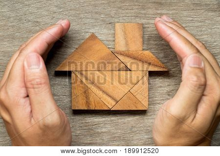 Hands hold the tangram puzzle in home shape (Concept for Home protection or insurance)