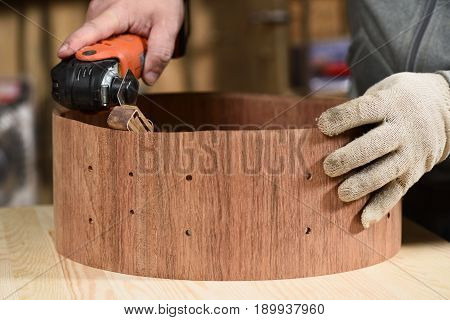 Carpenter grinding wooden drum shell with sandpaper closeup