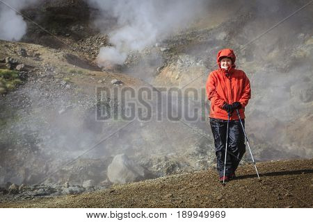 Hiker is standing near boiling springs in Reykjadalur Valley in South Iceland
