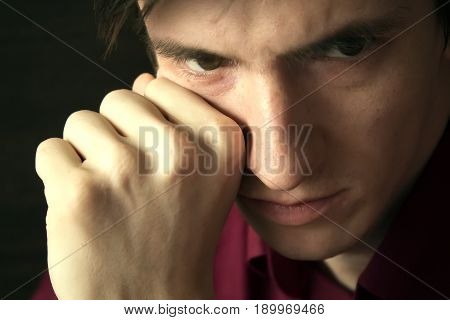 close-up portrait of a guy, a sad heavy look, a fist propping his cheek