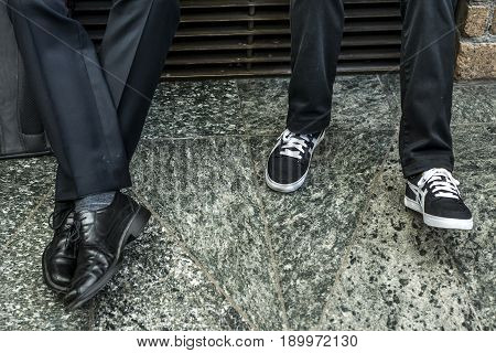 Closeup of two men in suit Variety Leather Shoes and black white sneaker