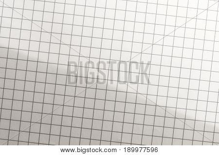 Graph paper in light and shadow and intentionally shot diagonally for more rapid or active feel. incandescent lighting tone. highlight on upper right. 
