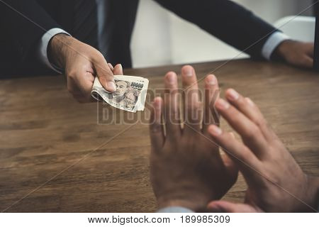Businessman refusing money Japanese yen bills - anti bribery and corruption concepts