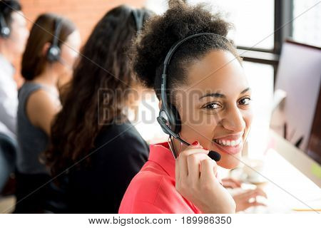 Smiling black businesswoman working in call center as the operator or telemarketer
