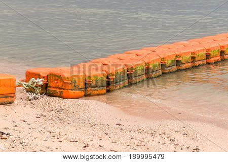 Close up line of dirt sea buoys fasten on sea beach marine equipment for marking safety zone.