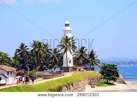 White lighthouse and palm trees in Galle Fort. Sunny day. Indian Ocean, Sri Lanka