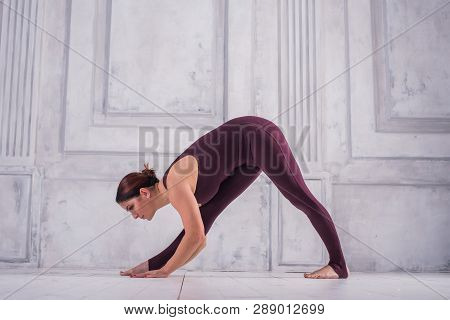 Woman Meditating In A Gym. Sporty Young Woman Doing Yoga Practice On Light Background.