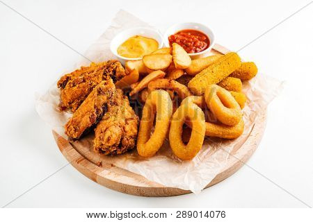 The beer plate with spicy chicken wings, calamari rings, fries onion rings, cheese balls, potatoes, breaded.