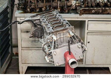 Replacement Six Cilinder Engine Used On A Red Crane Mounted For Installation On A Car After A Breakd