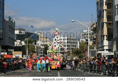 Limassol, Cyprus, March 10th, 2019: Men And Women In Bright Multi Colored Costumes In Front Of A Flo