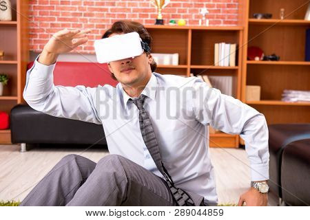 Young employee with virtual glasses during break in the office 