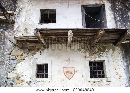 Facade With Broken Balcony, A Three Red Stars And A Red Coat Of Arms Of Slovenia. The House Is In An