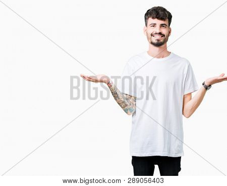 Young handsome man wearing white t-shirt over isolated background Smiling showing both hands open palms, presenting and advertising comparison and balance