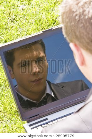 Joven empresario se refleja en su propia computadora.