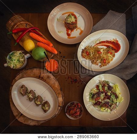 Healthy vegeterian food on brown wood board. Spring vitamin dieting food. Salad from beet with dried tomatoes and cabbage, potato vegan pancakes, dried tomatoes, pate from red beans, baked vegetables