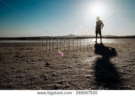 Single Man Walking On Dry Salt Lake In Limassol, Cyprus. Alone And Walking In Desert Conditions.