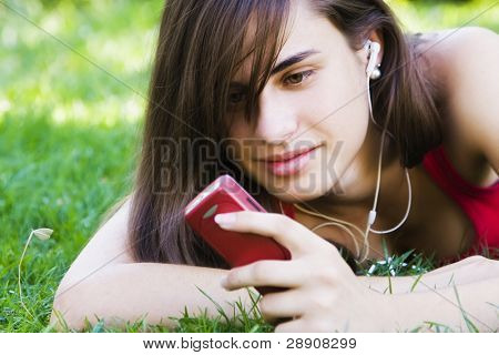 彼女の電話を使用して、公園で若い女性。