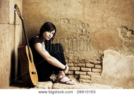 Lone trist guitarist i gamle brickwall.