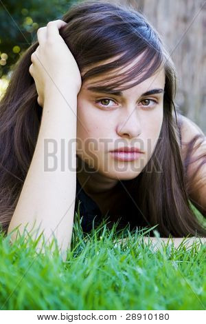 芝生の上を敷設若い見つめる女性