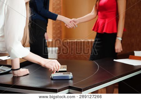Hand Swiping Debit Card On Pos Terminal, People In Office Holding A Conference And Discussing Strate