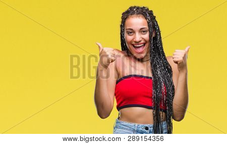 Young braided hair african american with pigmentation blemish birth mark over isolated background success sign doing positive gesture with hand, thumbs up smiling and happy. Looking at the camera