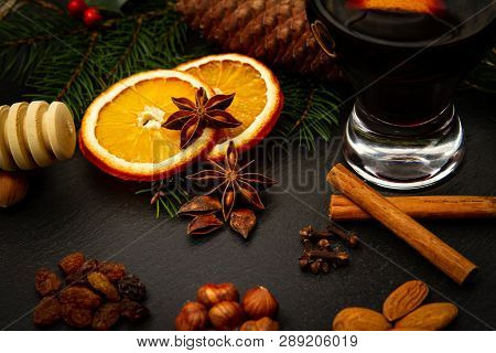 Homemade Mulled Recipe With Cinnamon, Star Anise, Dried Orange, Honey, Cloves, Raisins Over A Black 