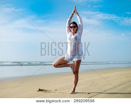 Young Woman Practicing Tree Yoga Pose Near The Ocean
