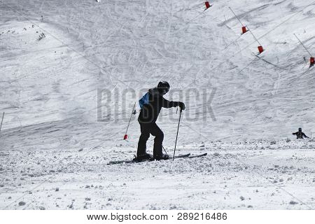 Male Skier Resting After Skiing. A Boy Standing In The Middle Of Downhill And Enjoy View To Valley O