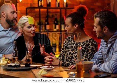 Group of friends playing sticky head game behind bar counter in a cafe