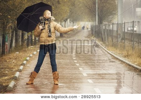 幸せな若いブロンドの女性は雨の日に。