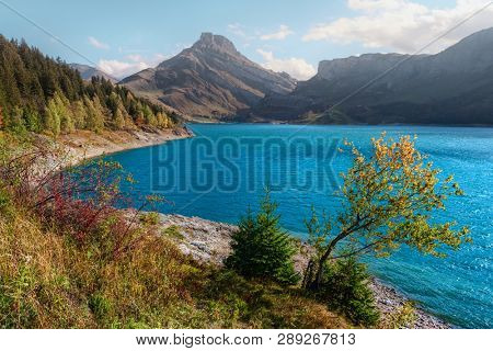 Sunny day on Roselend lake (Lac de Roselend) in France Alps. Blue water and high mountains in background. Landscape photography