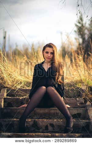 A Beautiful Brunette Girl Sitting On Stairs. Autumn. Art Photo.