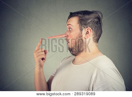 Side Profile Of A Shocked Liar Man With Long Nose Feeling Stunned Isolated On Gray Wall Background.