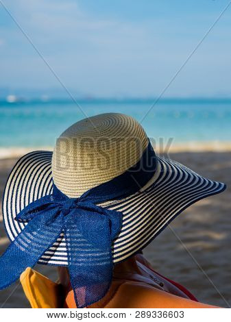 Woman with straw hat enjoying her holidays on a transat at the tropical beach in Thailand