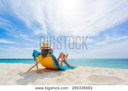Woman with straw hat enjoying her holidays on a transat at the tropical beach in Thailand