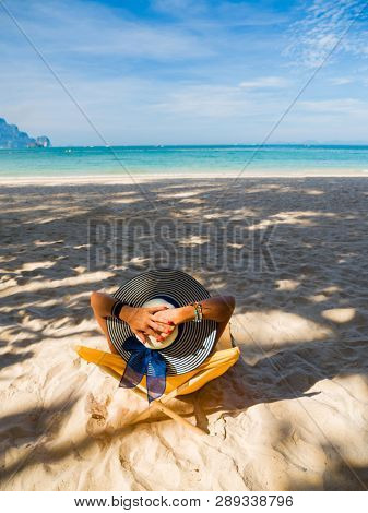 Woman with straw hat enjoying her holidays on a transat at the tropical beach in Thailand
